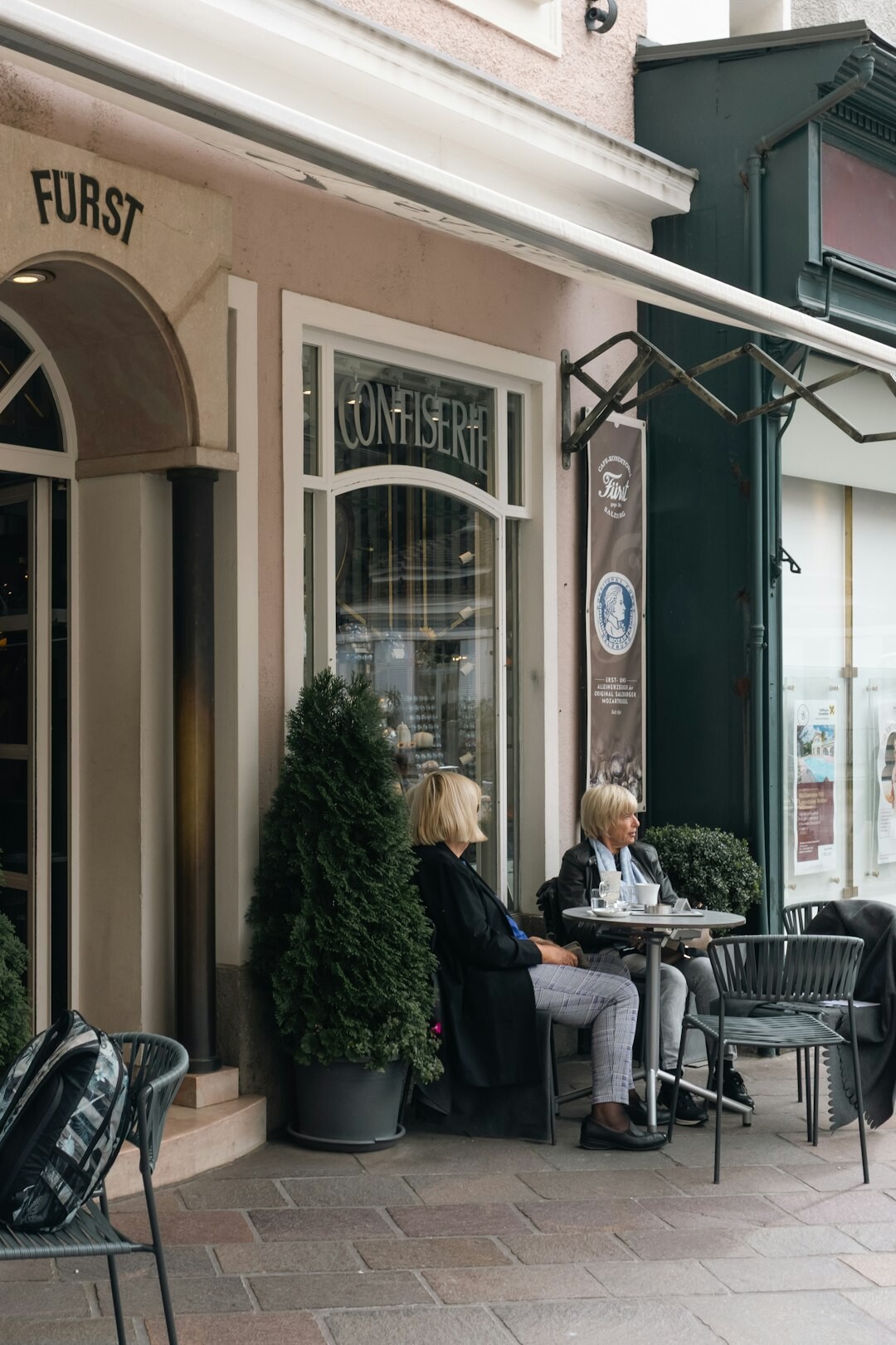 Two senior friends reading a newspaper together at a cafe table
